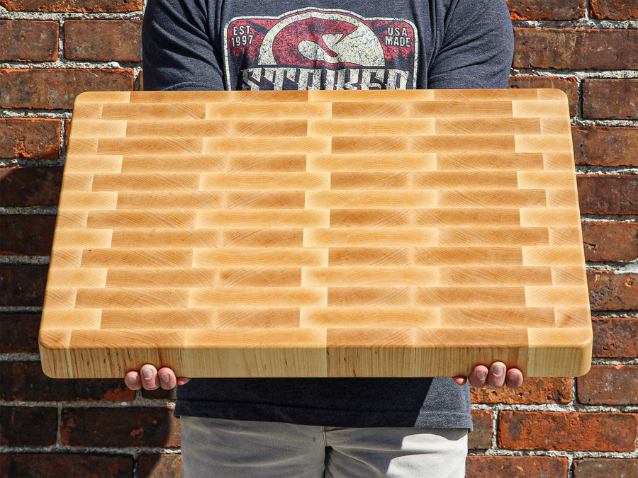 Person holding a large maple end-grain butcher block