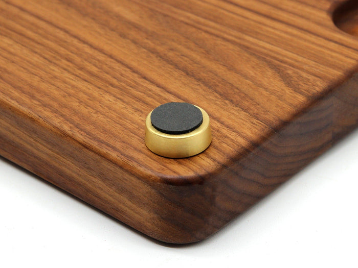 Brass cutting board foot with a black non-slip pad installed under a wooden board