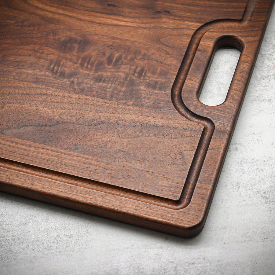 Close view of a walnut board's cutout handle and engraved name