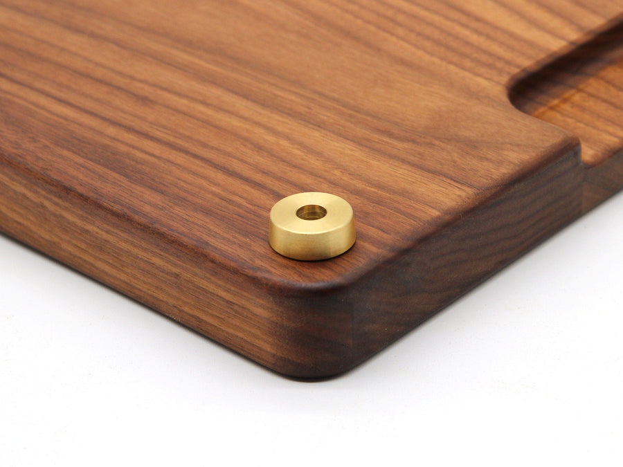 Solid brass foot attached to the corner of a walnut cutting board