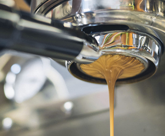Espresso flowing from a machine into a cup