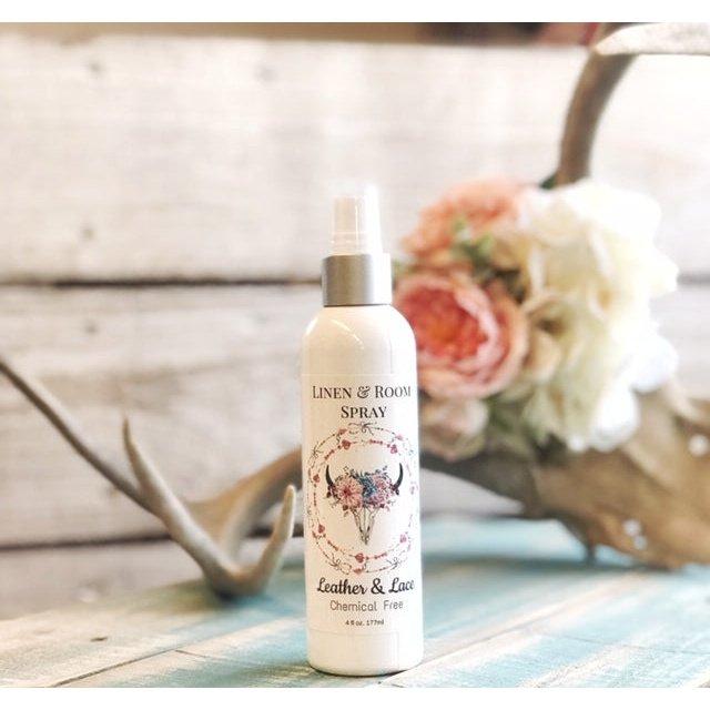 Leather and Lace room and linen spray bottle with a floral label displayed beside flowers
