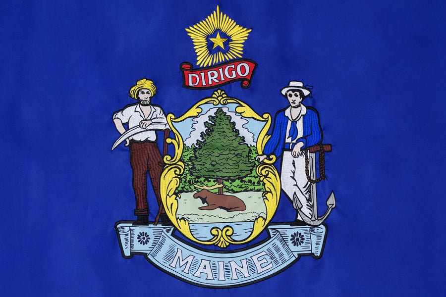 Maine state flag close-up with farmer seaman moose pine tree and Dirigo