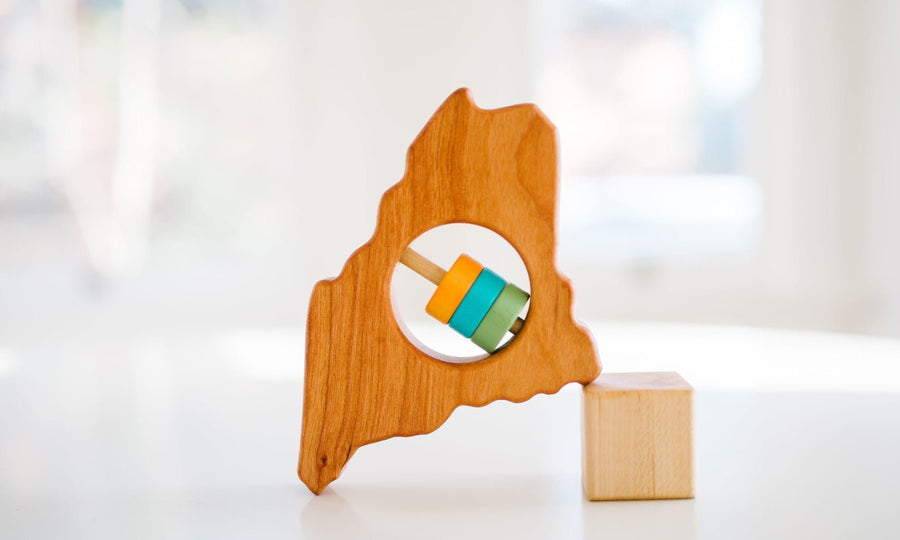 Maine state-shaped cherry wood baby rattle with colored center disks