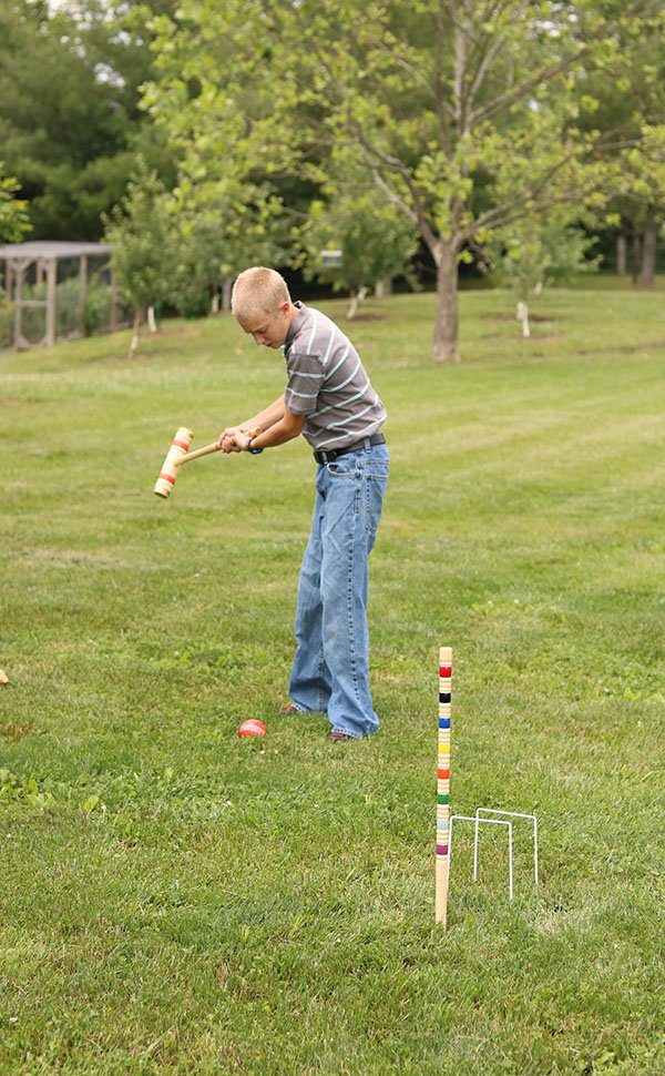 Player lining up a croquet shot on grass