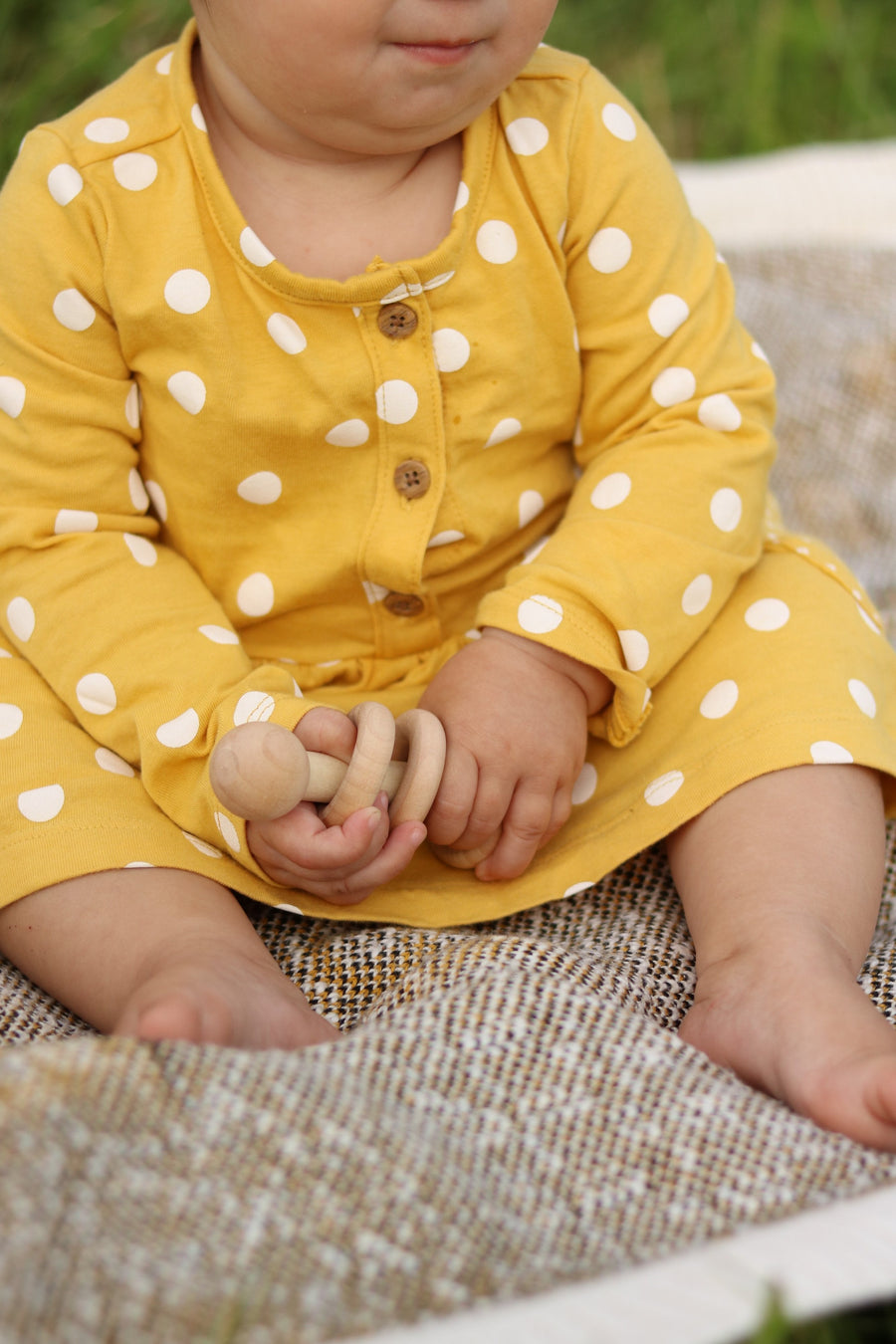 Baby holding a three-ring wooden rattle