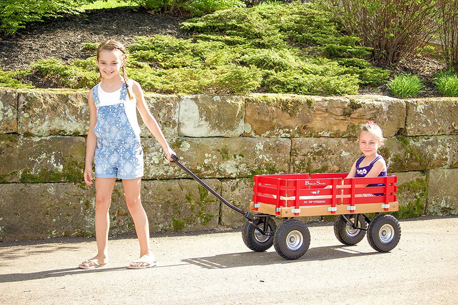 Child pulling a red wagon across grass