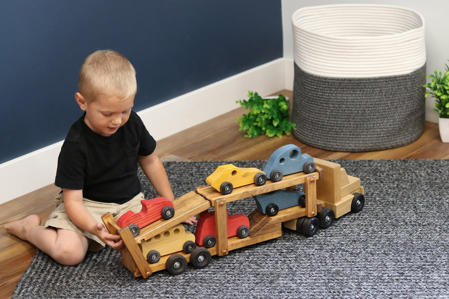 Child loading cars onto a wooden car-carrier truck