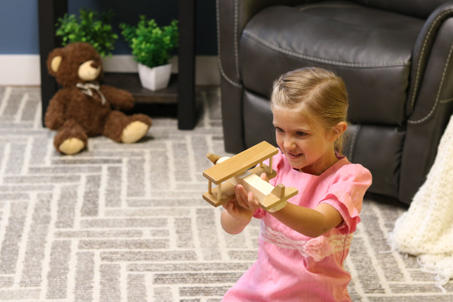 Child holding a wooden toy airplane