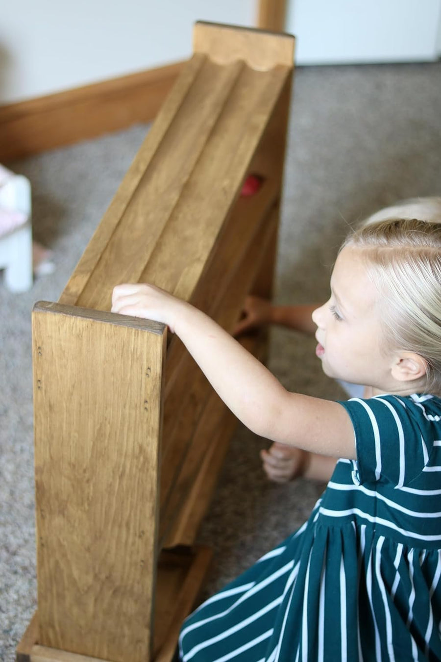 Children watching wooden balls move down a roller track
