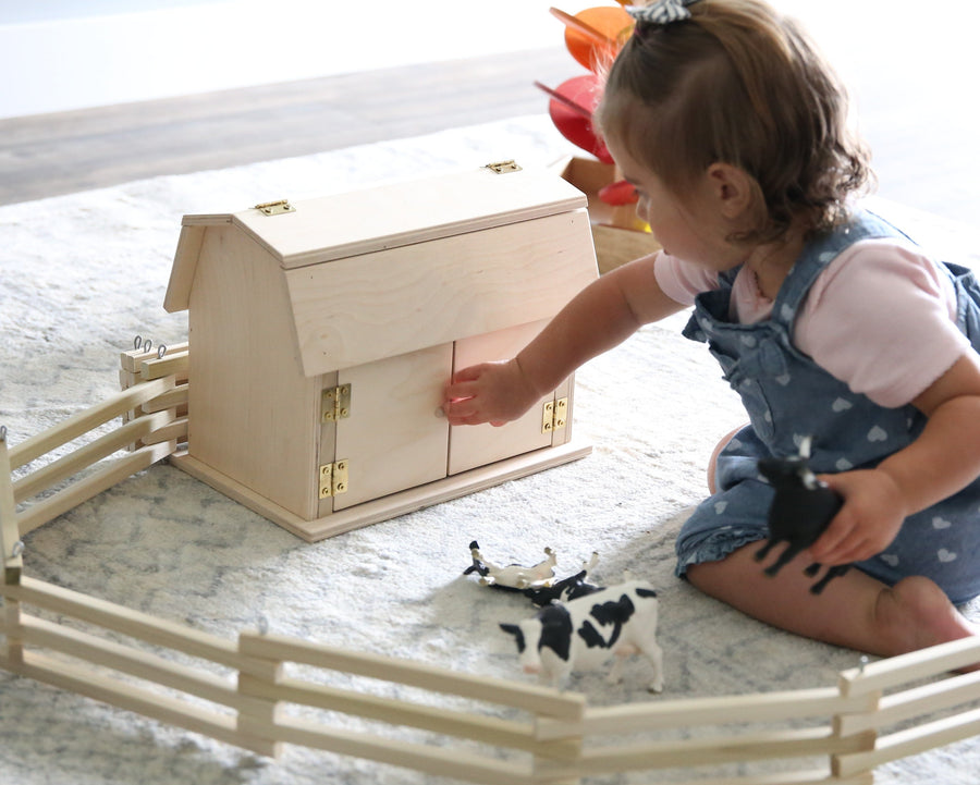 Child playing with a miniature wooden hip-roof barn