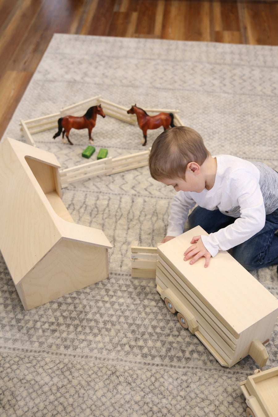 Child playing with a wooden ranch shed and farm animals