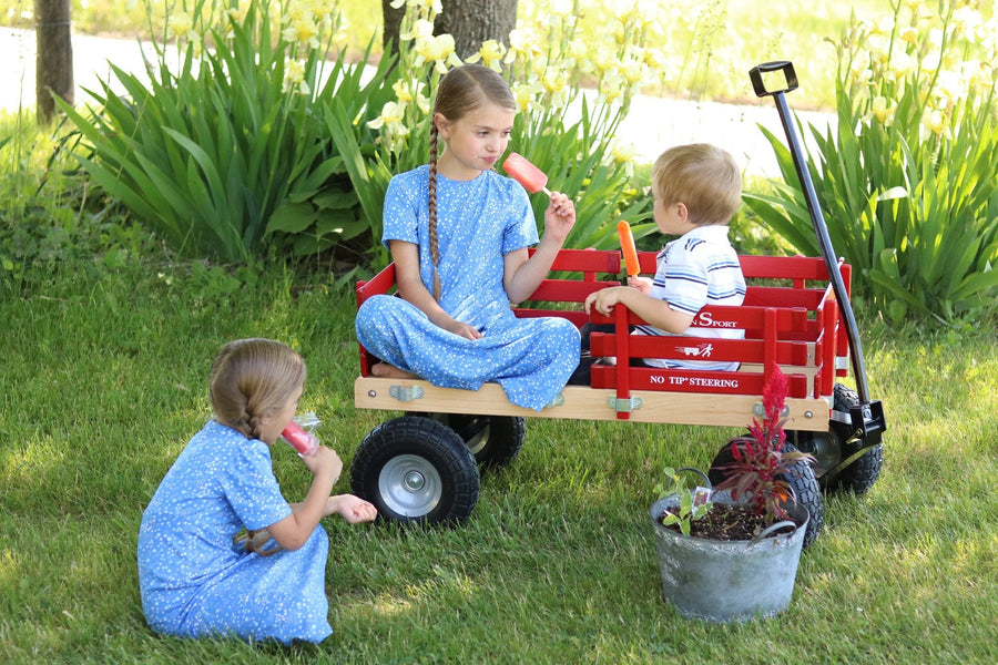 Children beside a red hardwood-and-steel wagon outdoors