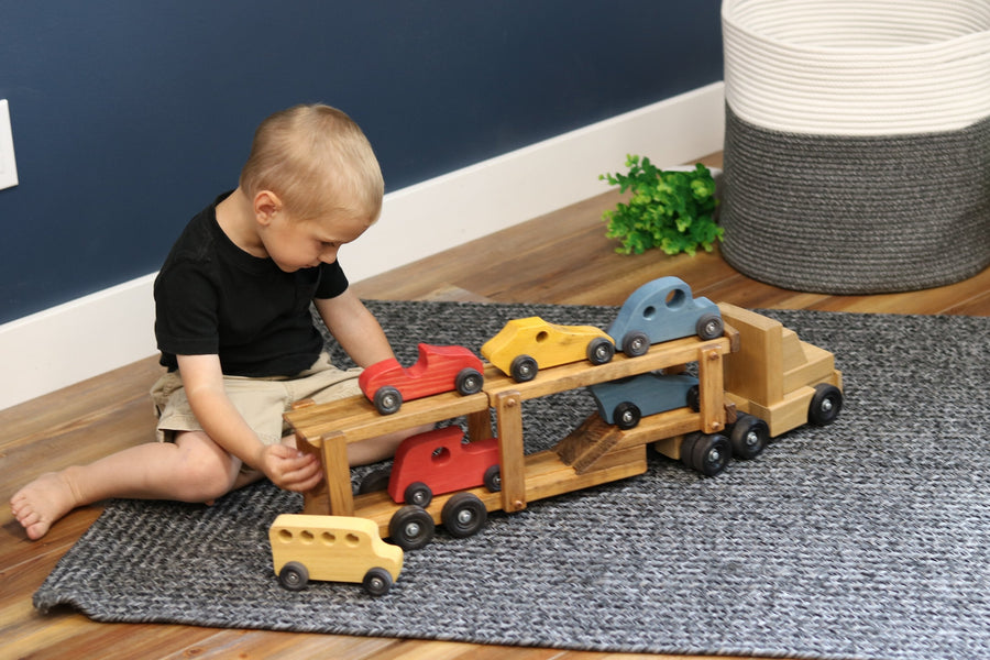 Child loading cars onto a wooden car-carrier truck