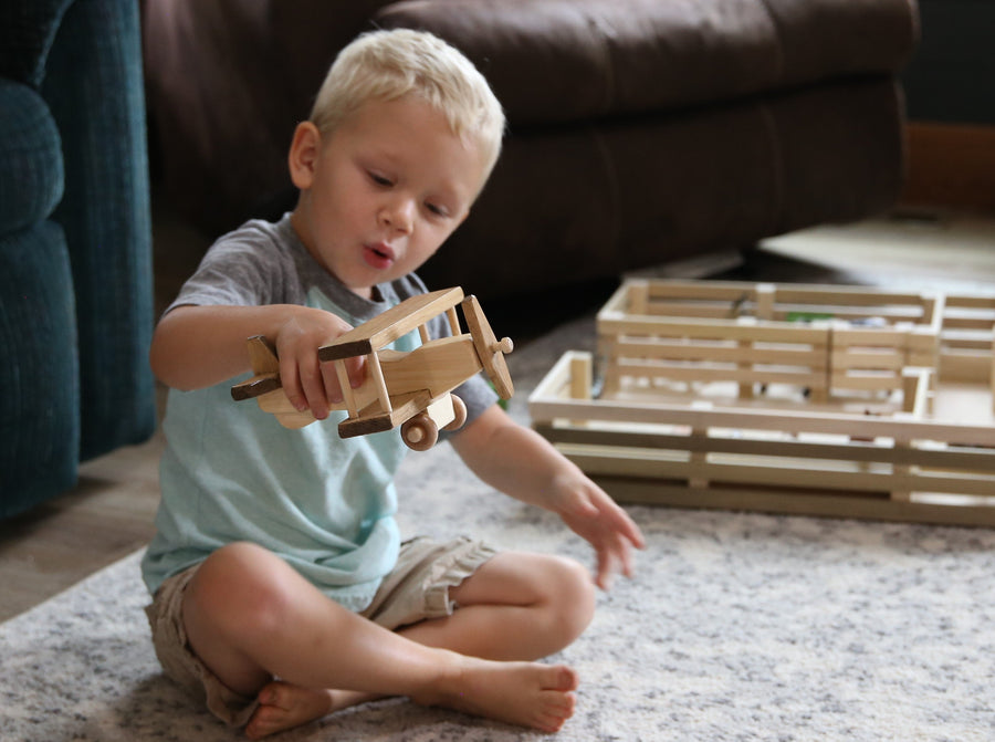 Child holding a wooden toy airplane