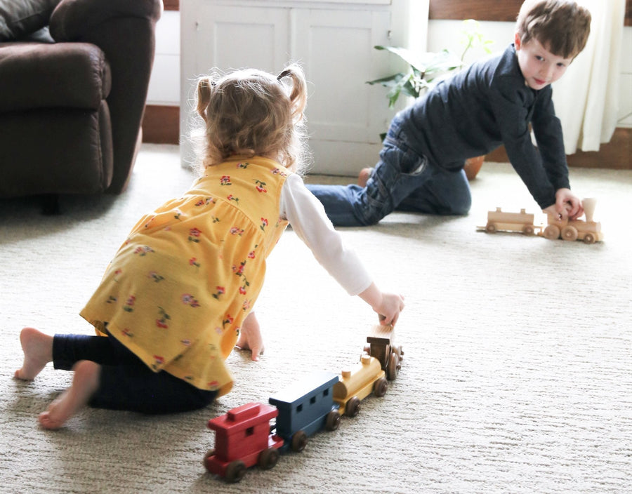 Children playing with a wooden train on the floor