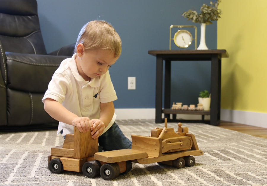 Child playing with a wooden truck and construction-vehicle trailer