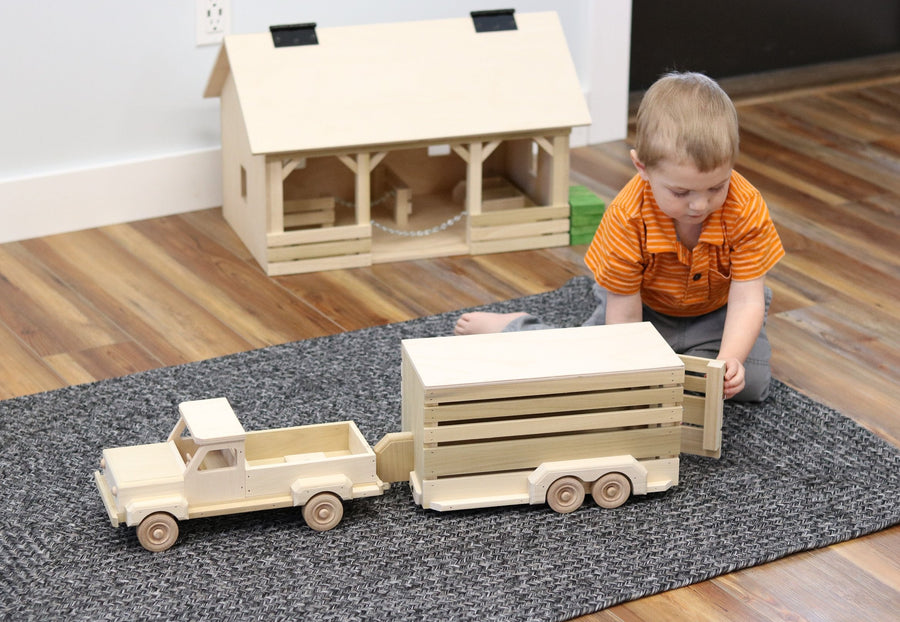 Child playing with a wooden pickup and horse trailer