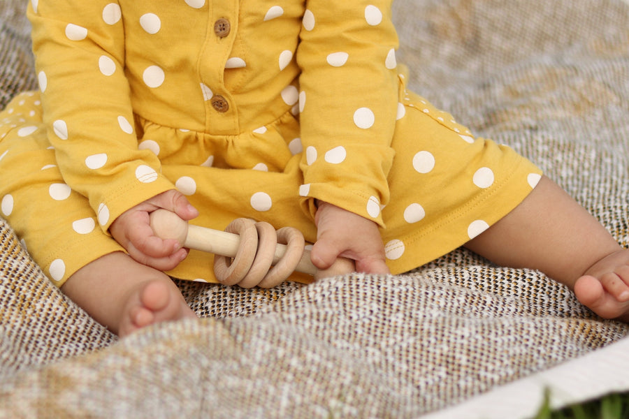 Baby holding a three-ring wooden rattle