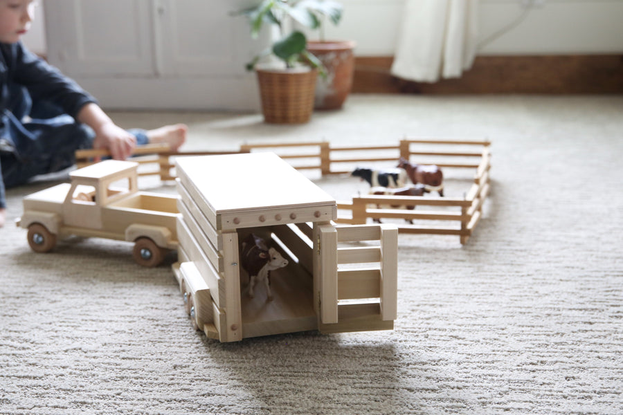 Wooden horse trailer with toy horses in a farm scene