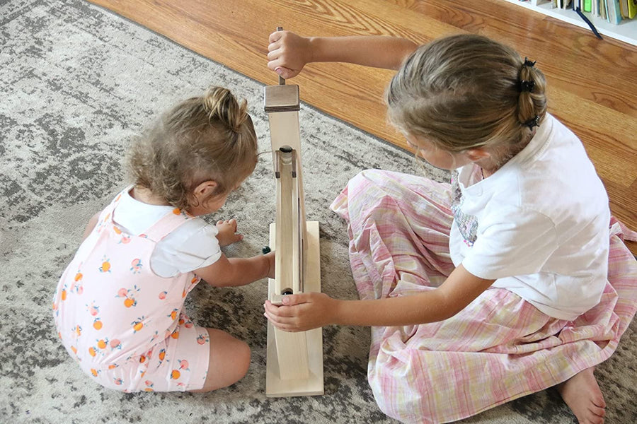Children operating a wooden marble pump toy
