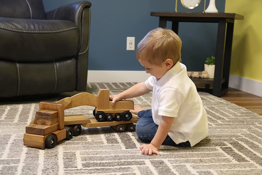 Child playing with a wooden truck and construction-vehicle trailer