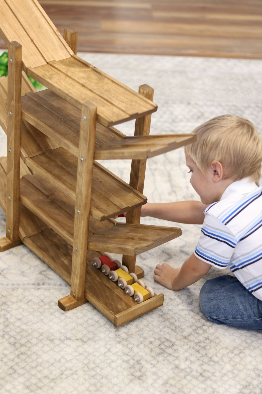 Child setting cars on a wooden roller racetrack