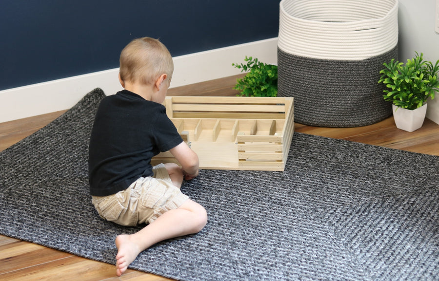 Child arranging toy animals inside a wooden miniature stockyard