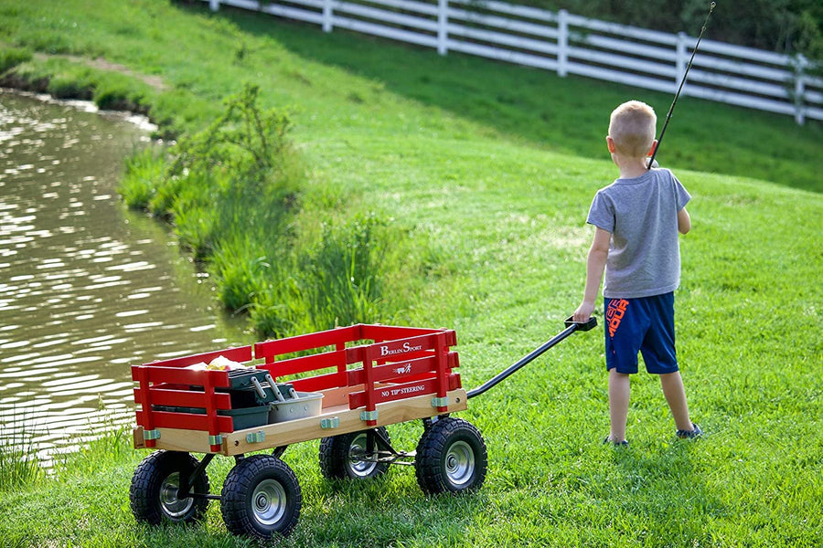 Child pulling a red wagon across grass