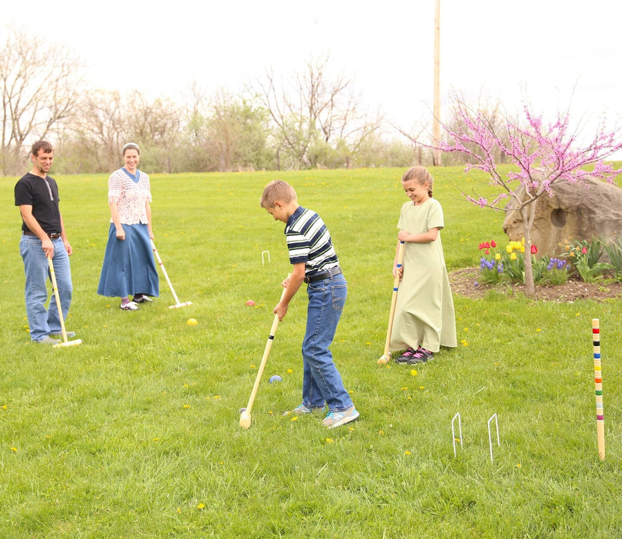 Family playing croquet together on a lawn