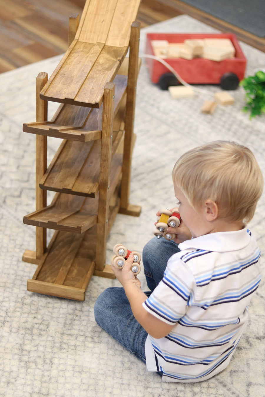 Child setting cars on a wooden roller racetrack