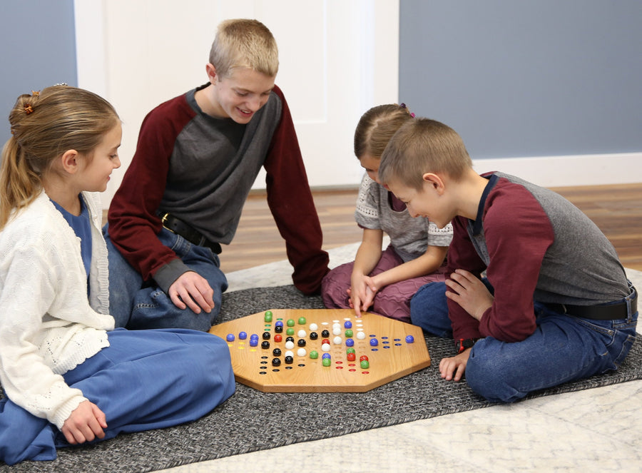 Players moving marbles on an oak Chinese Checkers board
