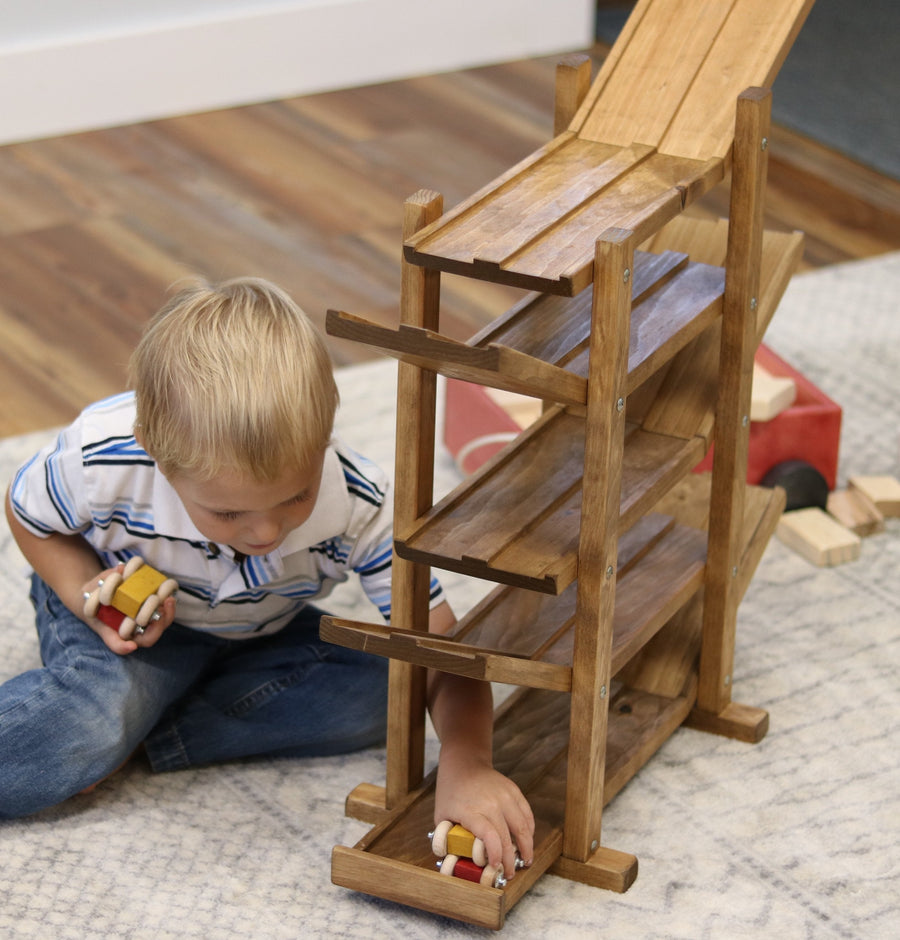 Child setting cars on a wooden roller racetrack