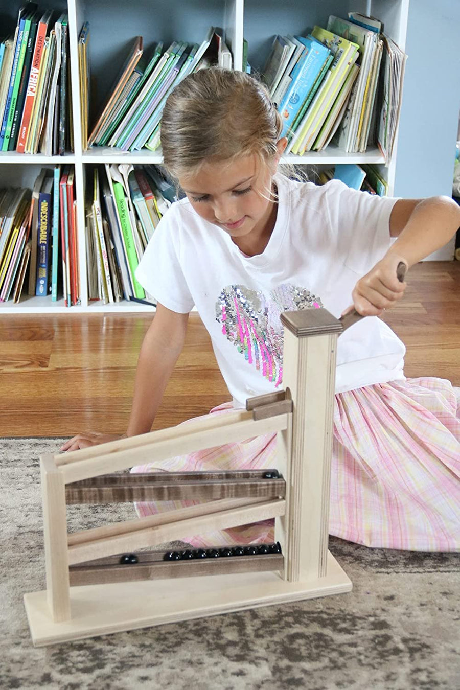 Children operating a wooden marble pump toy