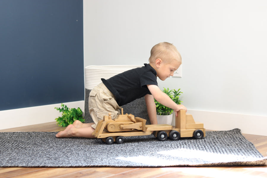 Child playing with a wooden truck and construction-vehicle trailer