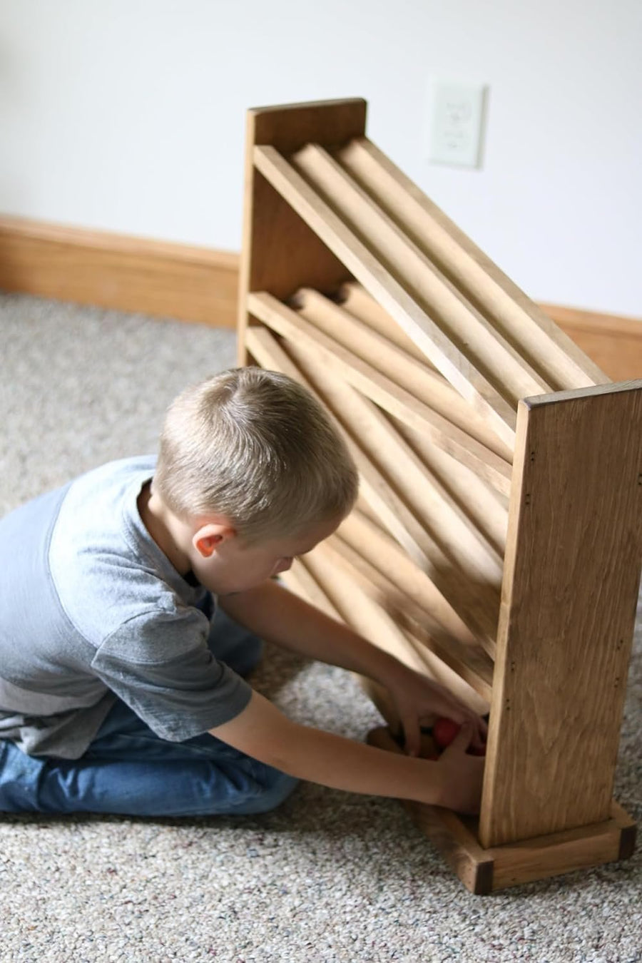 Children watching wooden balls move down a roller track