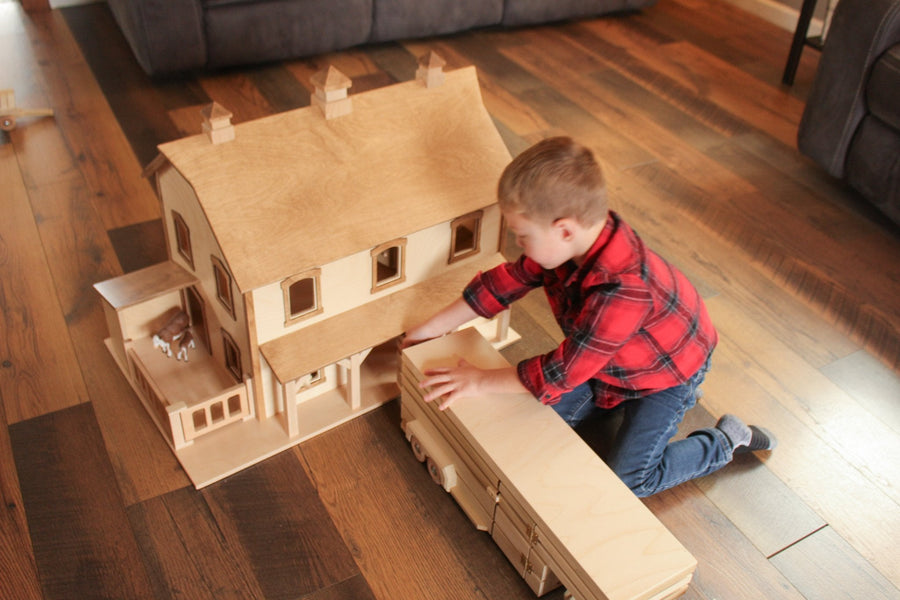 Child playing with a two-story wooden bank barn
