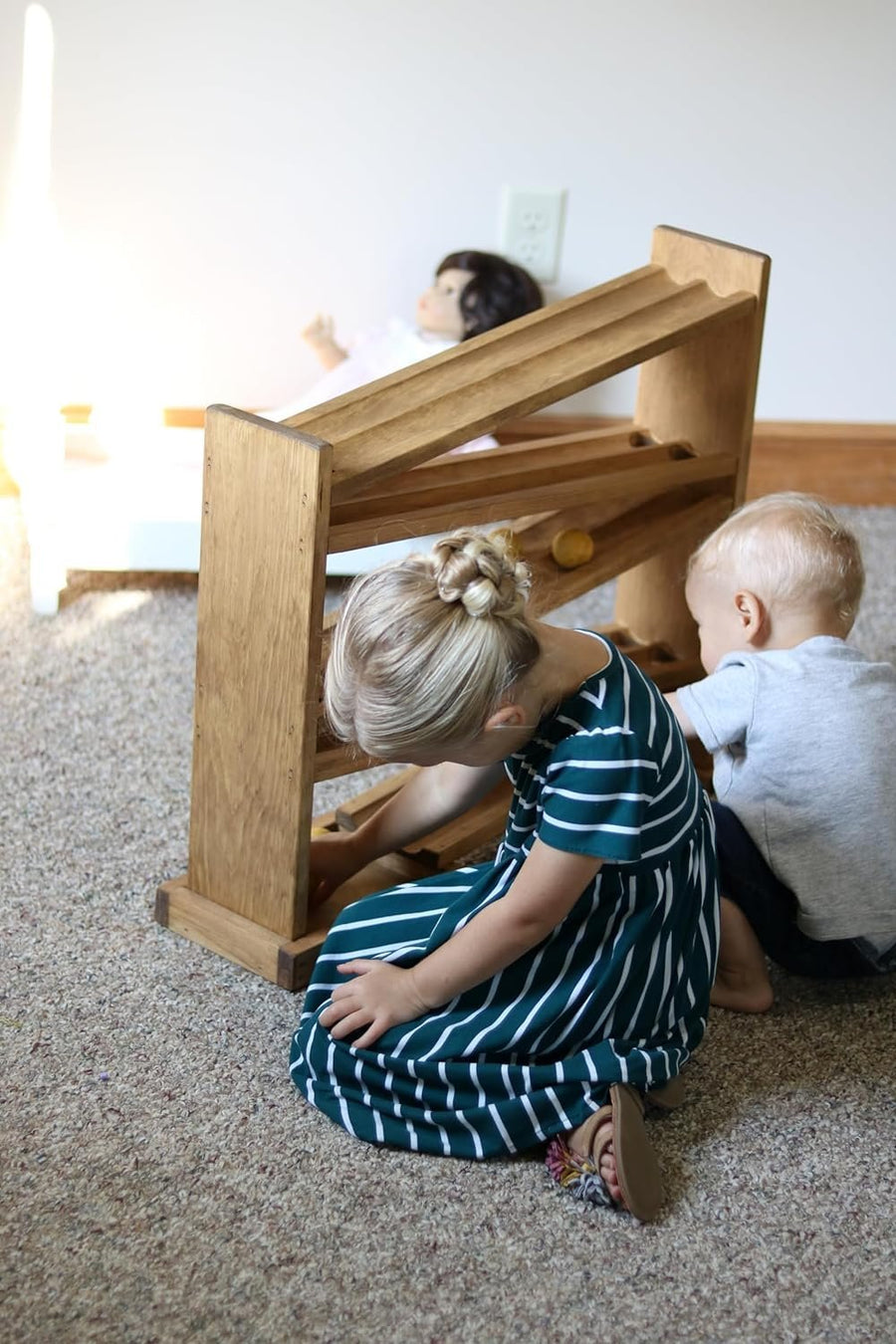 Children watching wooden balls move down a roller track