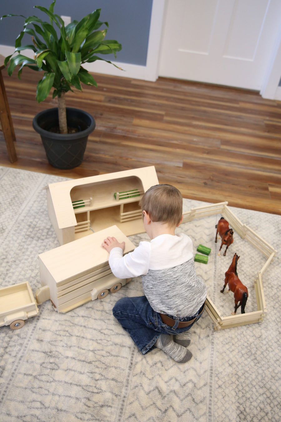 Child playing with a wooden ranch shed and farm animals