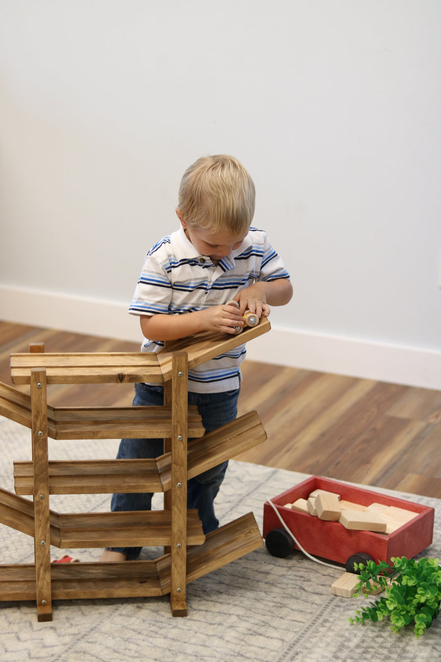 Child setting cars on a wooden roller racetrack