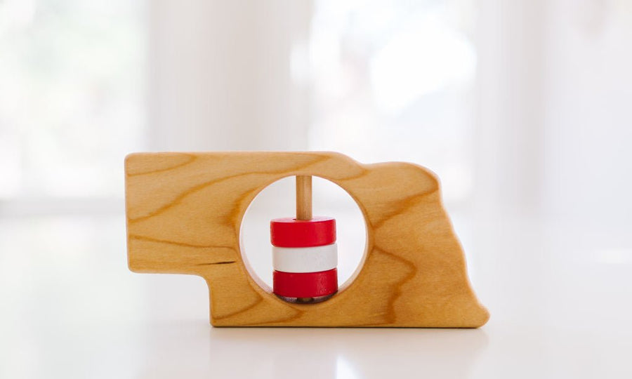 Nebraska state-shaped cherry wood baby rattle with colored center disks