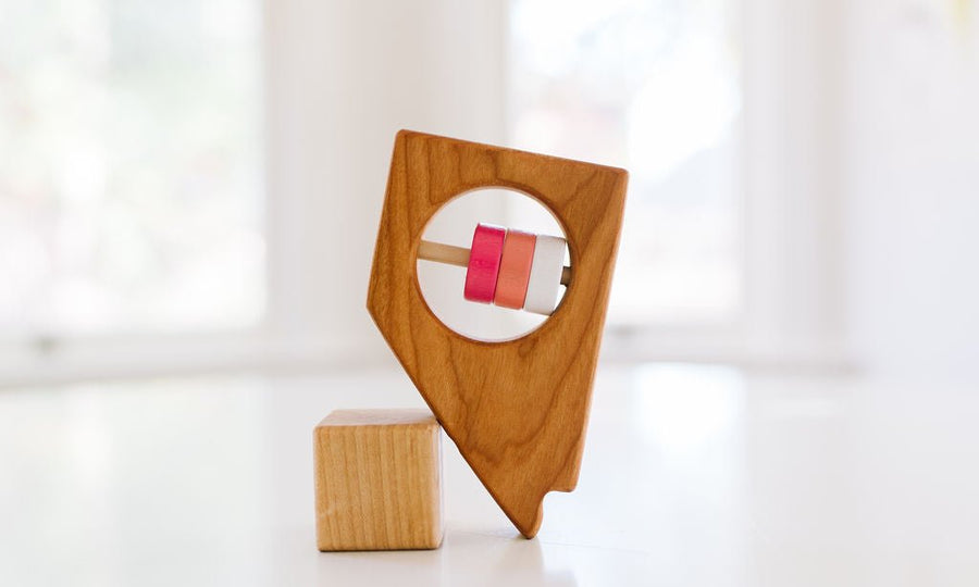 Nevada state-shaped cherry wood baby rattle with colored center disks