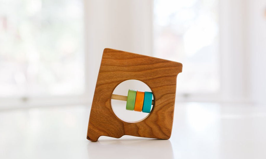 New Mexico state-shaped cherry wood baby rattle with colored center disks
