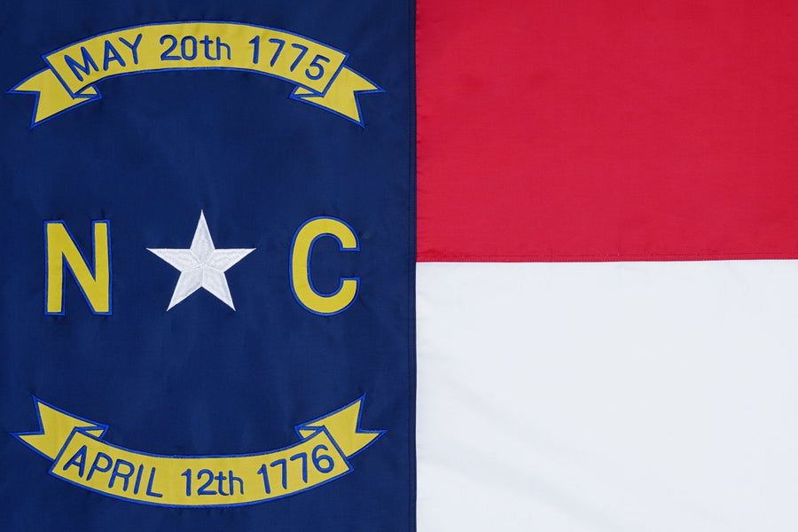 North Carolina state flag close-up with NC letters star and historic date ribbons