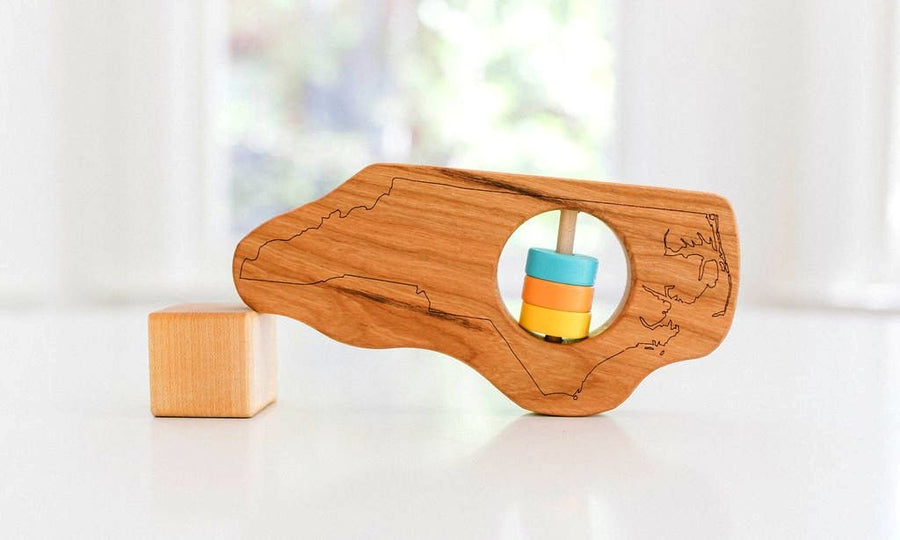 North Carolina state-shaped cherry wood baby rattle with colored center disks