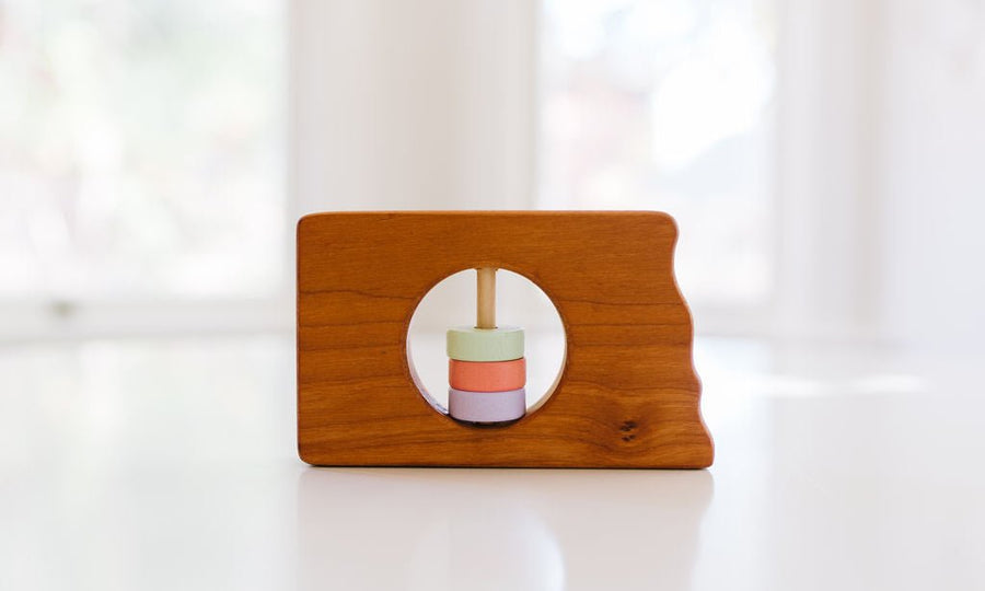 North Dakota state-shaped cherry wood baby rattle with colored center disks