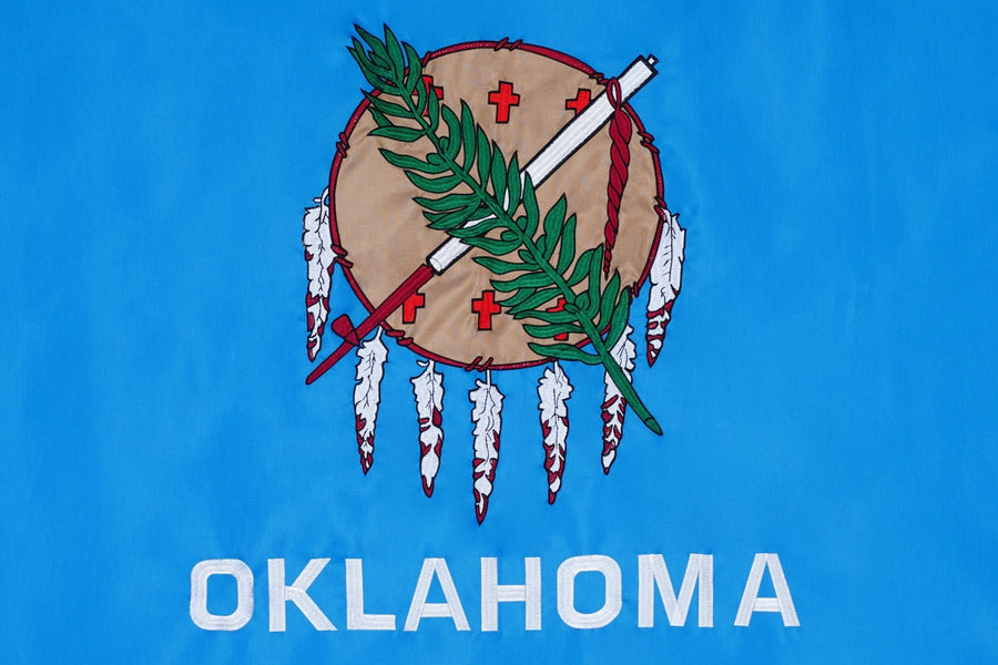 Oklahoma state flag close-up with shield peace pipe olive branch and feathers