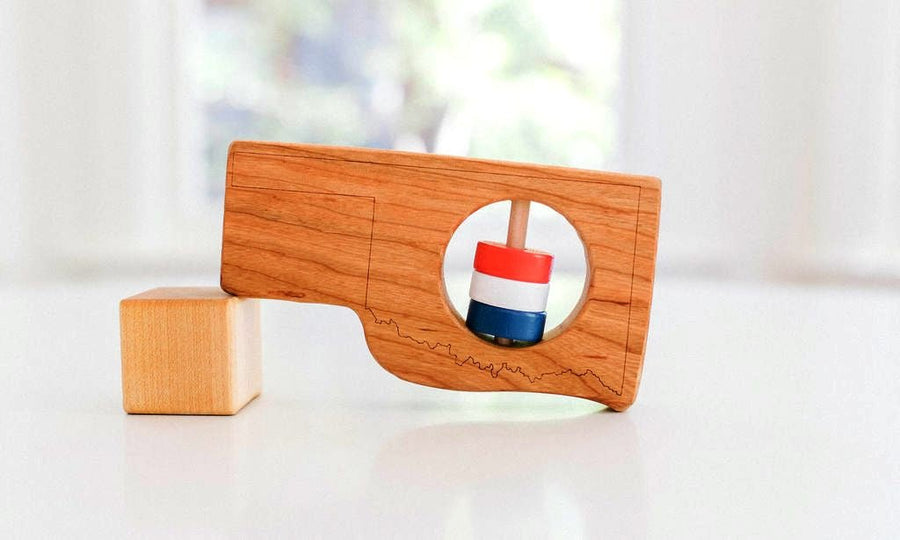Oklahoma state-shaped cherry wood baby rattle with colored center disks