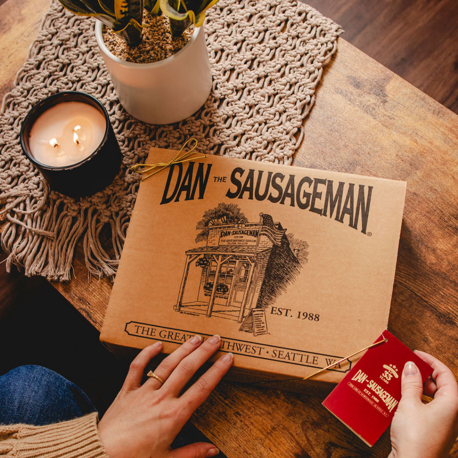 Closed Dan The Sausageman kraft gift box with red gift tag on a table