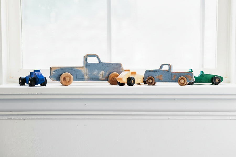 Colorful wooden toy pickup trucks lined up on a windowsill